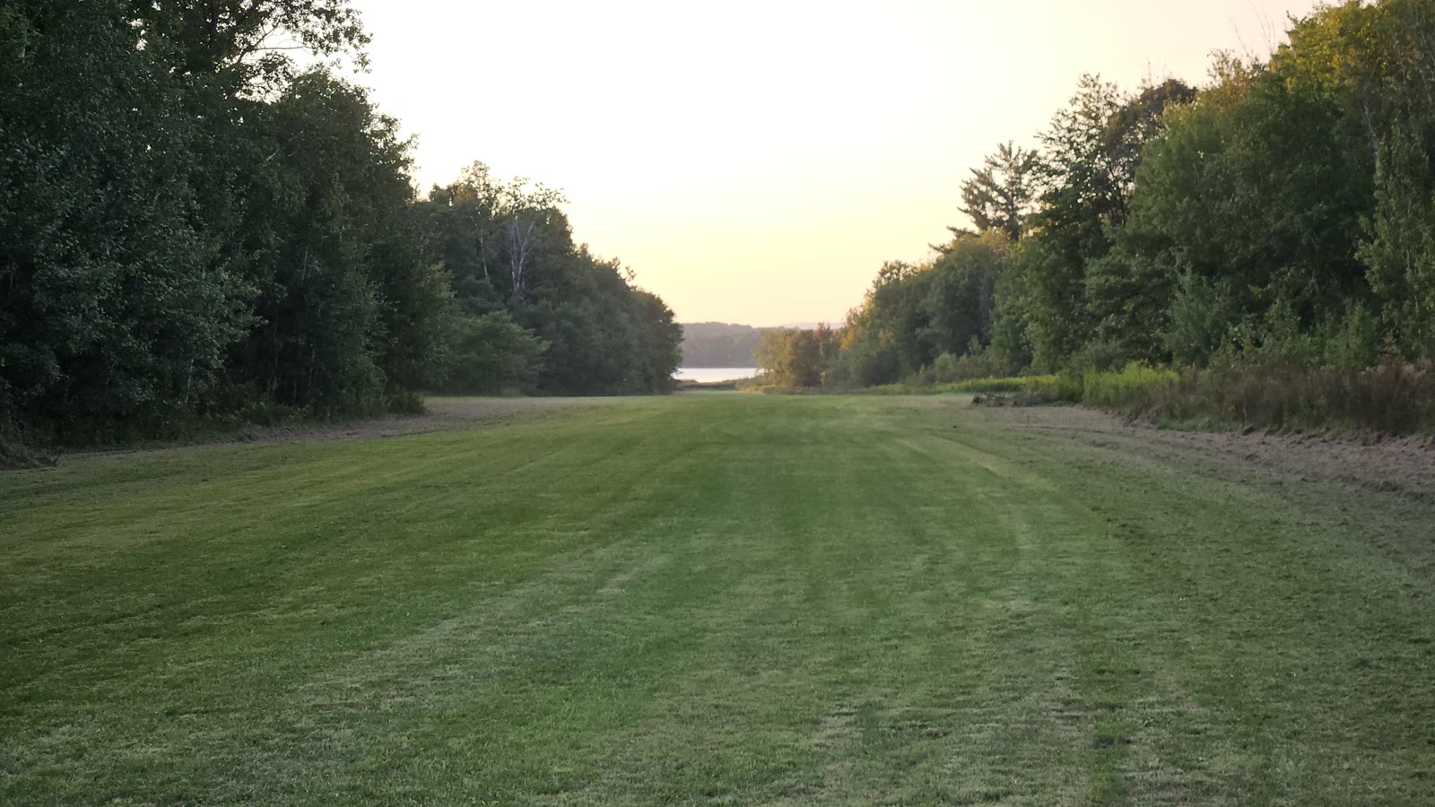 Grass runway at Round Lake Airport with the lake visible at the far end